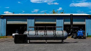 Custom made 1000 gallon smoker in front of a metal shop.